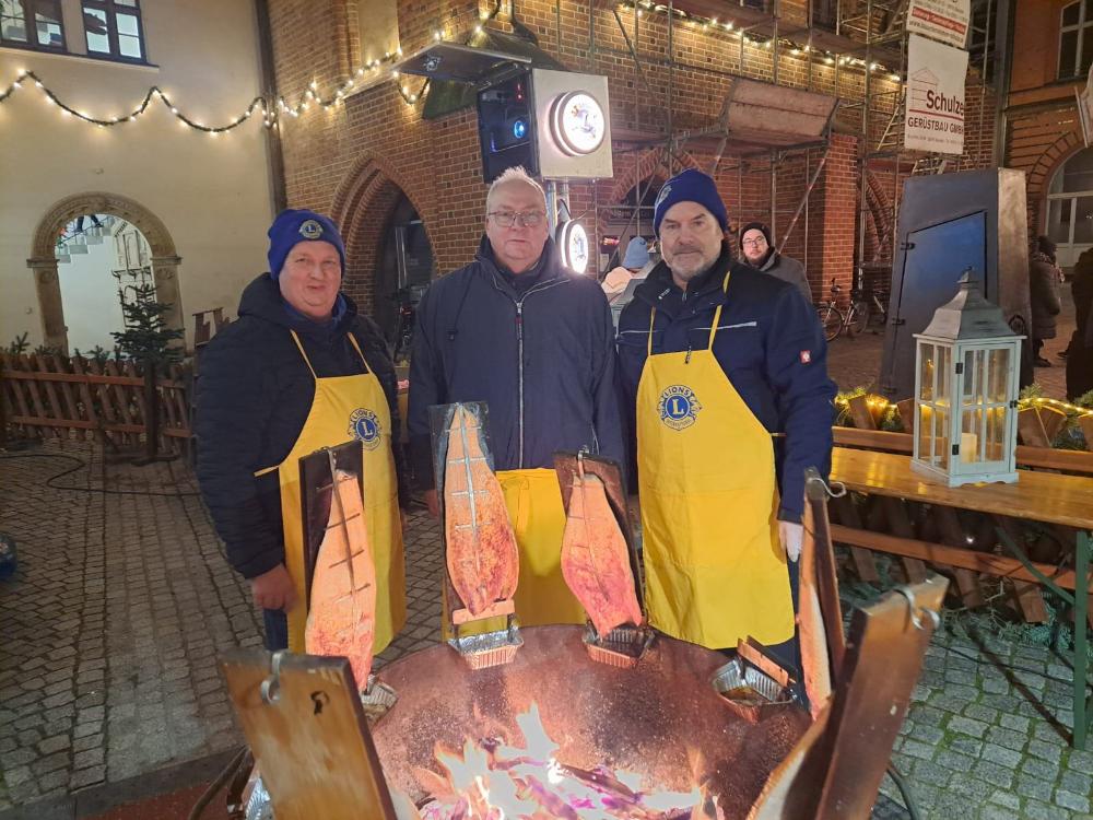 ZeitungsfächerLionsfreunde überwachen das Grillen der Lachsseiten am Feuer